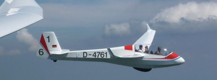 Ein Doppelsitziges Segelflugzeug, der hintere Pilot zeigt Stinkefinger.