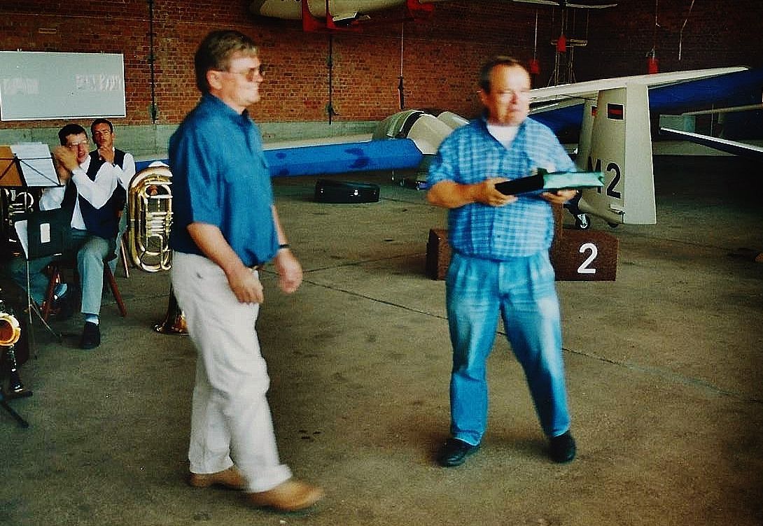 Zwei Männer in einem Flugzeughangar, im Hintergrund Segelflugzeuge.