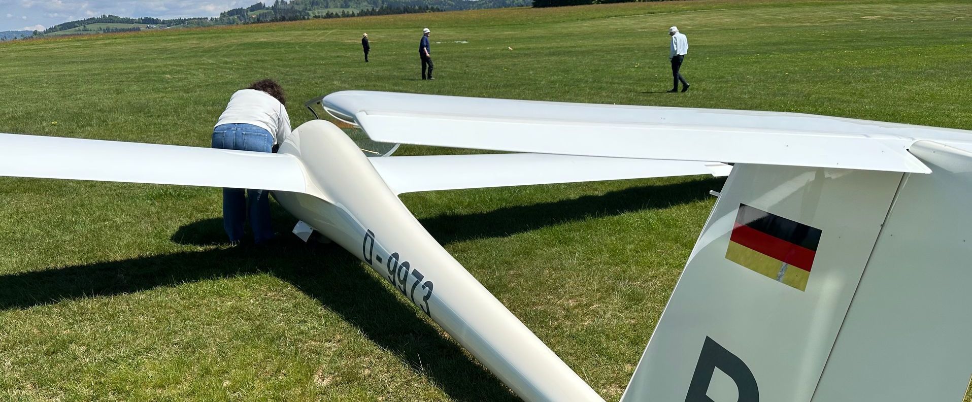 Ein Segelflugzeug von links hinten fotografiert, jemand beugt sich von außen ins Cockpit