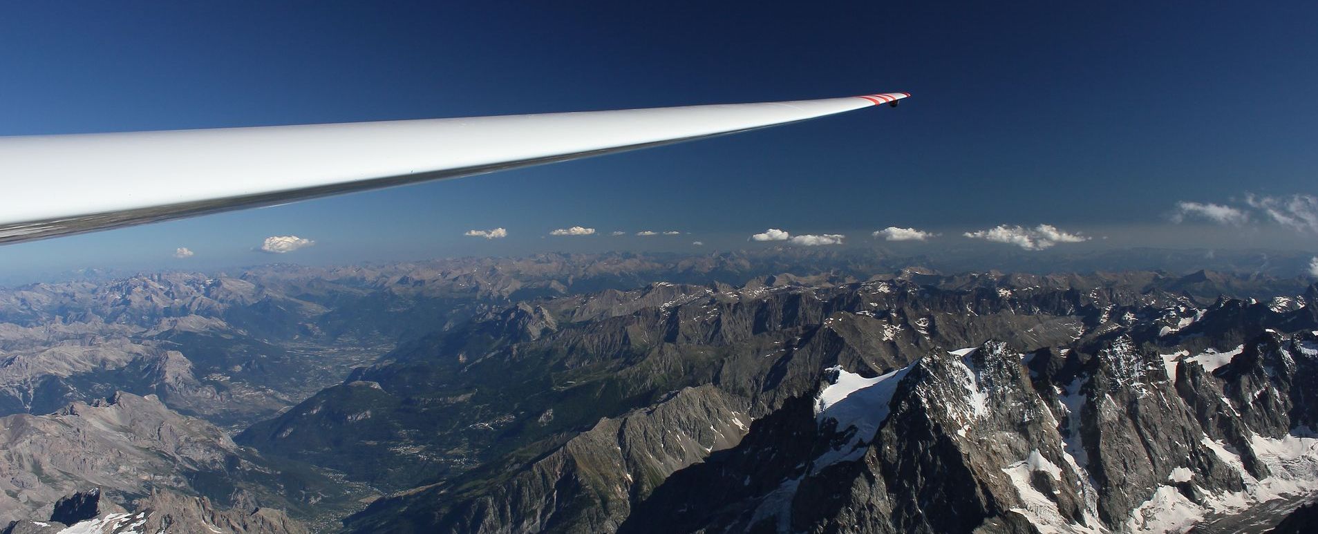Aus dem Segelflugzeug zur Tragfläche hin fotografiert über die Alpen hinweg bei bestem Wetter.