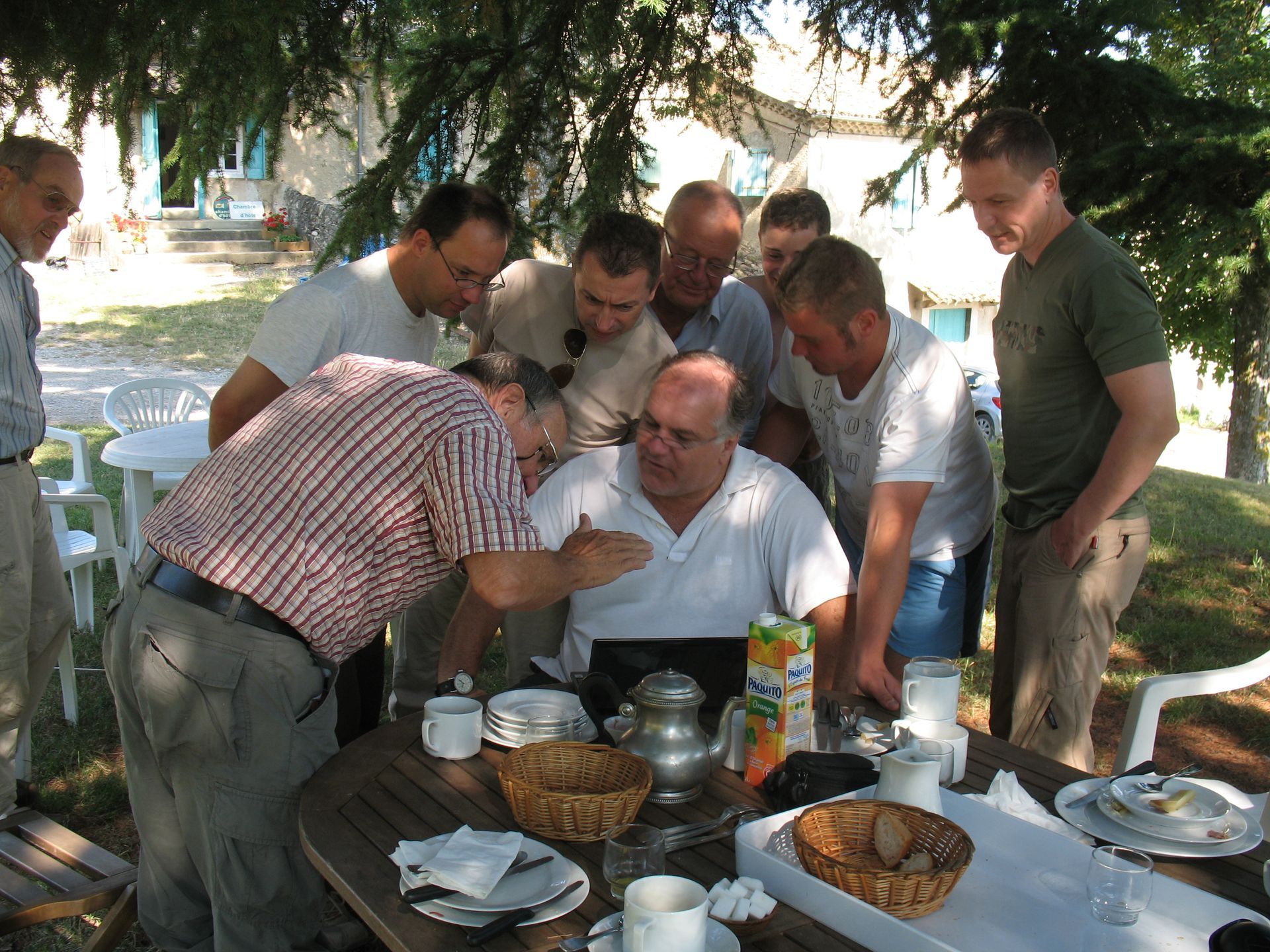 Mehrere Männer drängen sich um einen Mann mit Laptop herum.